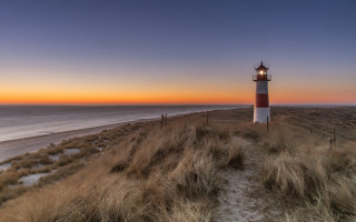 Lighthouse grassy hill ocean sunset 2 - radiant free wallpaper for desktop