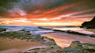 Sunset rocky beach water cityscape - a sunset over a rocky beach free wallpaper