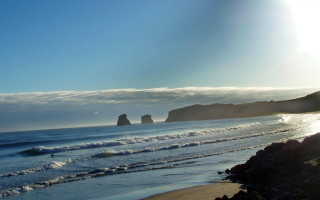 Beach rock formation surfboard ocean - a surfboard in the foreground free wallpaper