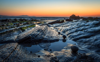 Sunset rocky beach water mountain - a sunset over a rocky beach free wallpaper