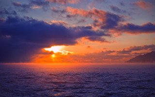 Sunset ocean boat mountain clouds - the water and a mountain in the distance free wallpaper