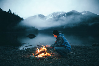 Fire sitting man lake mountains - free vintage wallpaper
