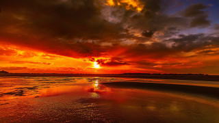 Sunset red sky clouds ocean - a surfboard in the foreground free wallpaper