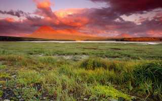 Mountain field water grass sunset 2 - a mountain in the background and a body of water free wallpaper