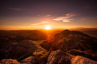 Sunset mountain range rocky sky - a bright sun in the distance free wallpaper