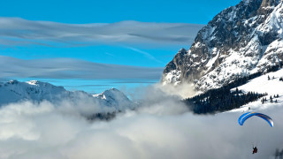 Paraglider mountains clouds snow matte - over a mountain range free wallpaper
