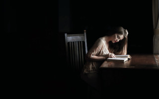 Woman sitting reading dark window - in the dark free wallpaper