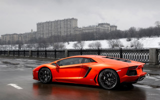 Bright orange sports car wet - a clock tower in the background free wallpaper