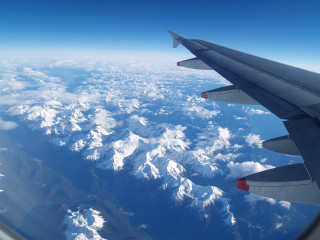 Plane wing mountain snow capped - over a mountain range free wallpaper