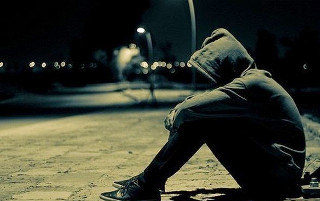 Person sitting head down street - a street light in the background free wallpaper