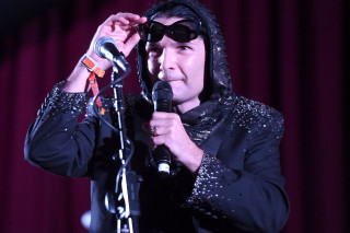 Man black jacket sunglasses microphone - a red curtain behind free wallpaper