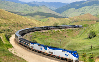 Train mountainside city traveling tracks - a mountain in the background free wallpaper