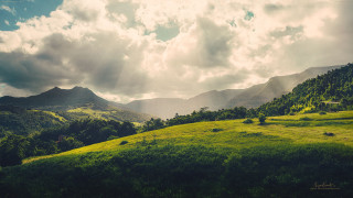 Lush green hillside cloudy sky - a lush green hillside free wallpaper