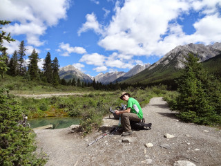 Man sitting rock river mountains - his lap free wallpaper