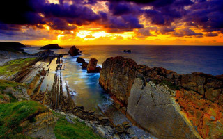 Sunset rocky beach water rock - a large rock formation in the foreground free wallpaper