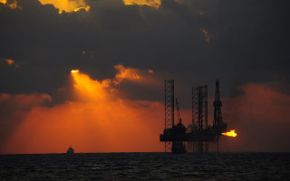 Oil rig water cloudy sunset - a large body of water under a cloudy sky free wallpaper