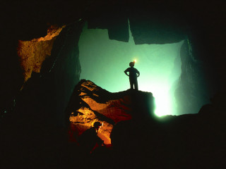 Man standing cliff cave flashlight - a flashlight free wallpaper for desktop
