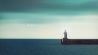 Lighthouse pier ocean cloudy sky - a sunbeam in the distance free wallpaper