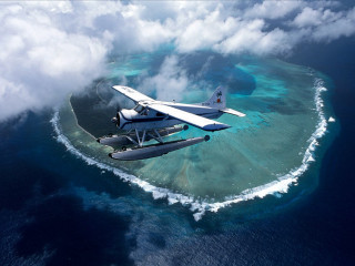 Plane flying small island ocean - anson maddock free wallpaper