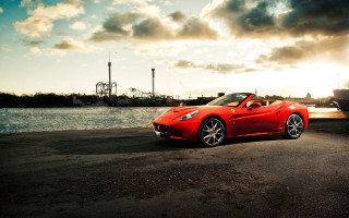 Red sports car road water - a boat in the background free wallpaper